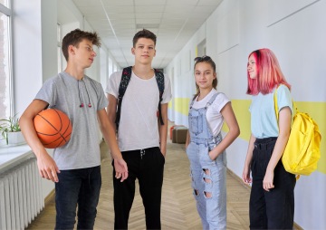 4 teenageři stojí ve škole