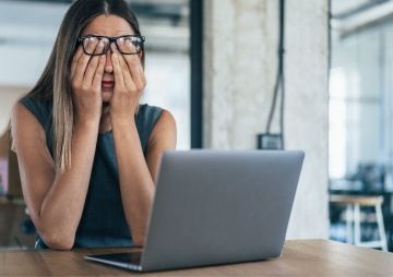 Žena s brýlemi si zakrývá oči