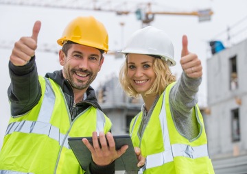 Muž a žena v helmách a reflexních vestách se usmívají a ukazují palec nahoru