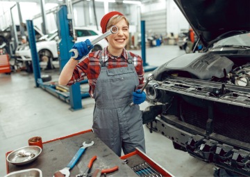 Dívka v autoopravně v montérkách se usmívá