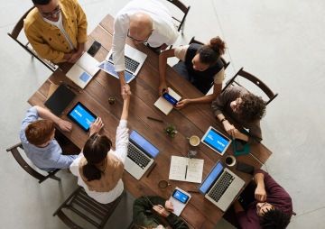 Skupina lidí sedí u stolu a spolupracují