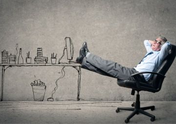 Muž má nohy na stole a nepracuje