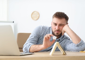 Muž je znuděný a hraje si s papírem a kartami