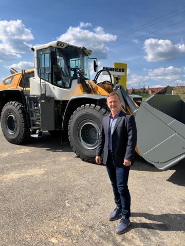 Jaroslav Moravec stojí před bagrem značky Liebherr CZ s. r. o.