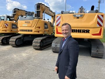 Jaroslav Moravec stojí před stavebními stroji značky Liebherr